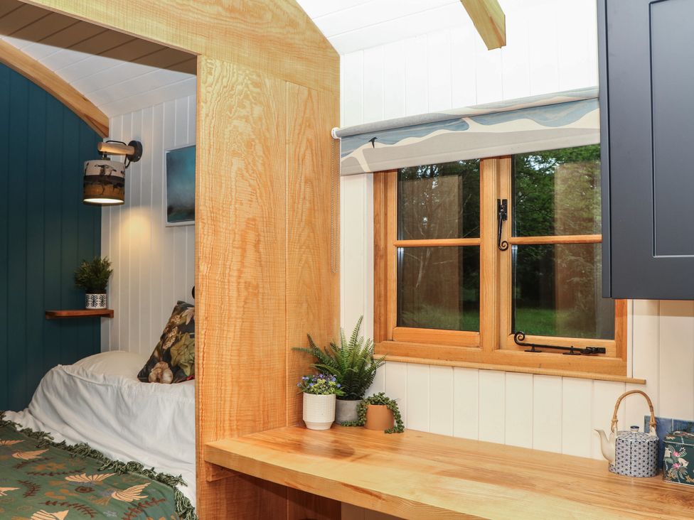 A bedroom with a bed and a table at Ridden Brake shepherds hut Yelverton