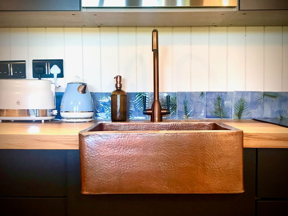 A kitchen with a copper sink and modern appliances at Goldcrest in Postbridge