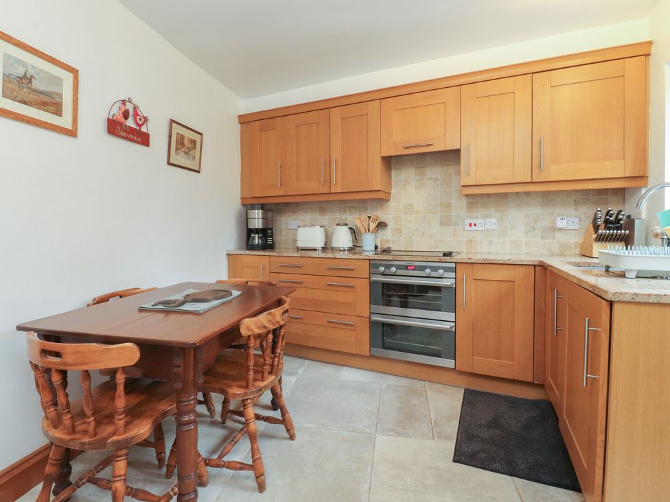 A kitchen with wooden cabinets and a dining table at The Cottage in Giggleswick
