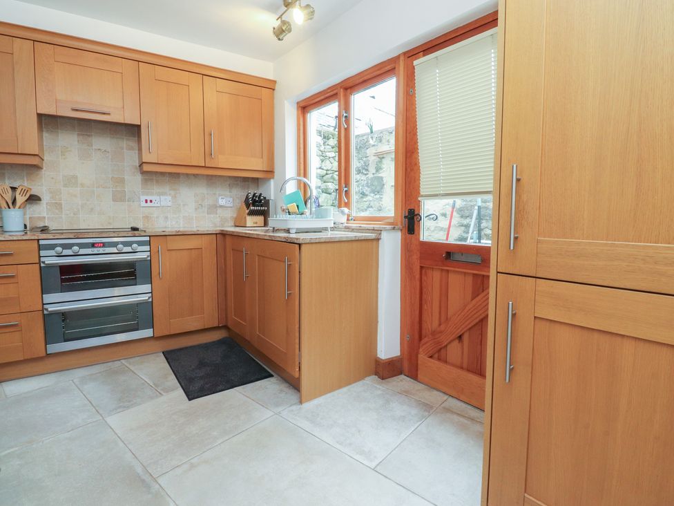A kitchen with wooden cabinets and an oven at The Cottage in Giggleswick