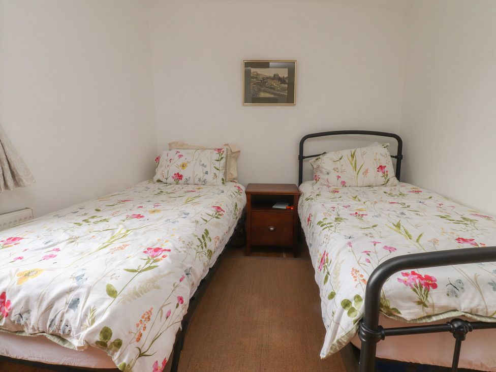 A bedroom with two single beds and a bedside table at The Cottage in Giggleswick