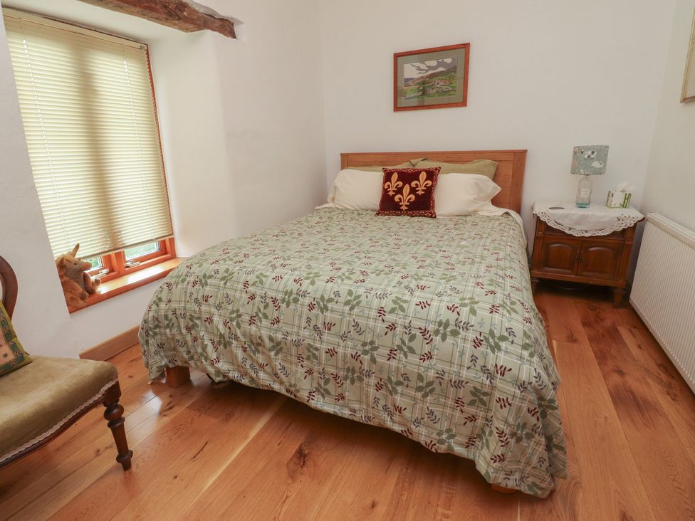 A bedroom with a bed and chair at The Cottage in Giggleswick