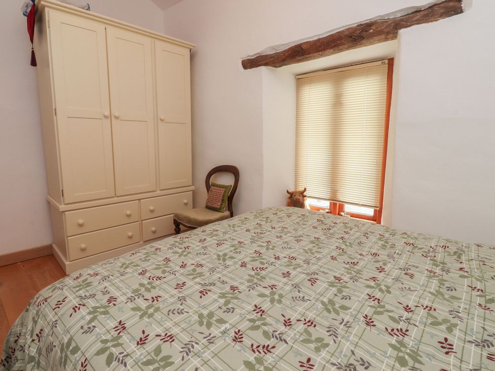 A bedroom with a bed and a wardrobe at The Cottage in Giggleswick