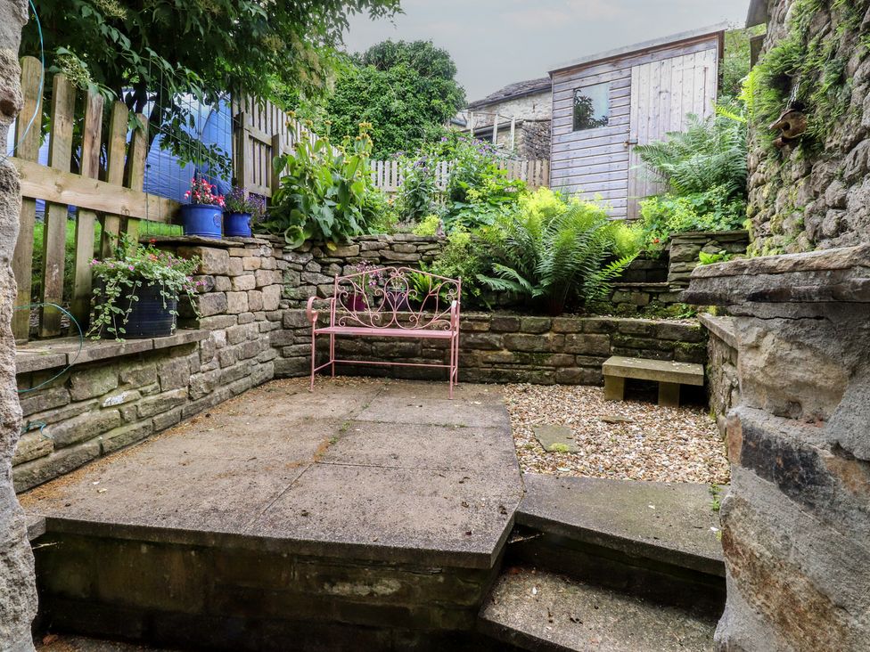 A garden with a bench and flower pots at The Cottage in Giggleswick