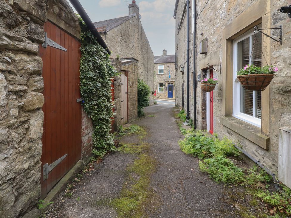 A pathway between stone walls with doors and plants at The Cottage in Giggleswick