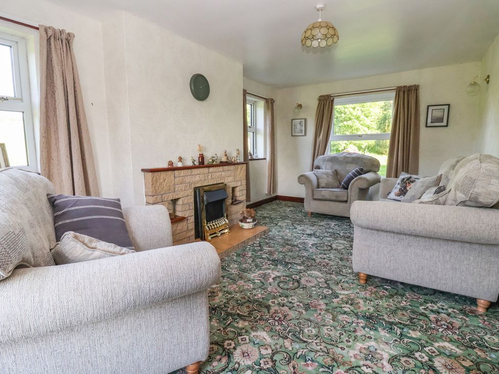 A living room with a fireplace and sofas at Robin Hood Farmhouse in Keswick