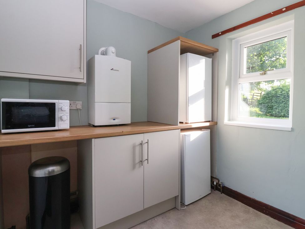 A kitchen with a microwave, fridge, and cupboard at Robin Hood Farmhouse in Keswick