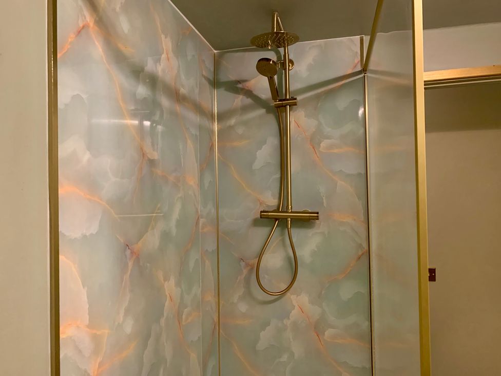 A shower with gold fixtures and patterned tiles at Downton I Alnwick
