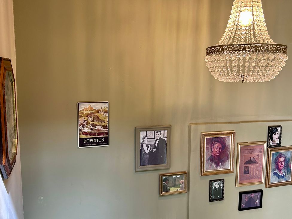 A staircase with a chandelier and framed pictures at Downton I in Alnwick