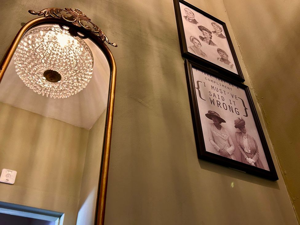 A mirror and framed photographs on the wall at Downton I in Alnwick