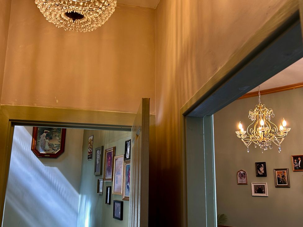 A hallway with a chandelier and framed pictures at Downton I Alnwick