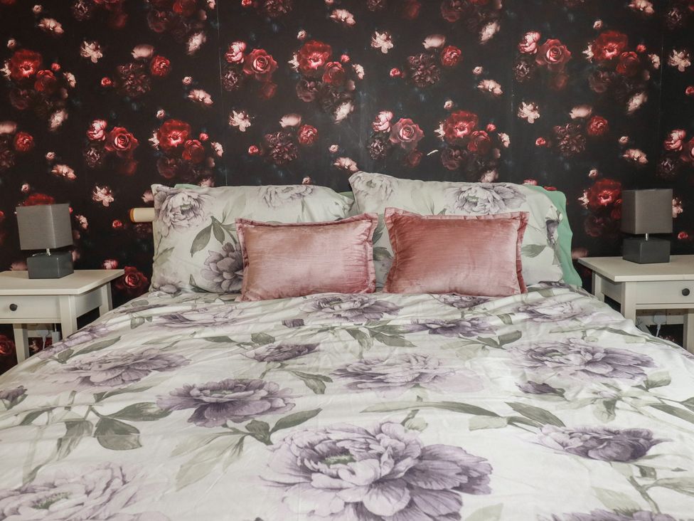 A bedroom with a bed and bedside tables at Treetops St Blazey