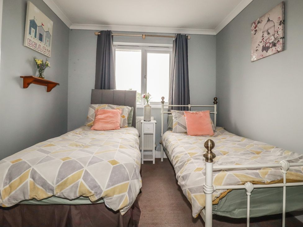 A bedroom with two single beds and a bedside table at Treetops in St Blazey