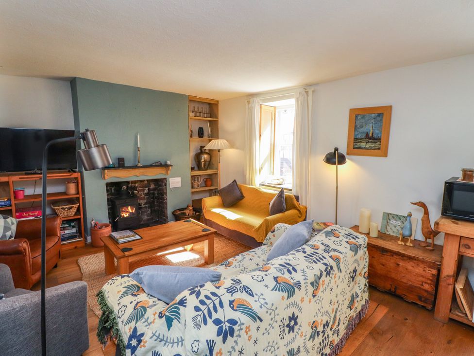 A living room with a sofa, television, and fireplace at Scoops’ Nook in Caernarfon