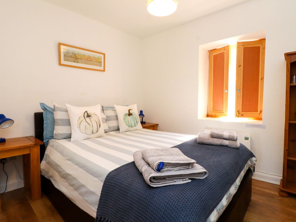 A bedroom with a bed, bedside tables, and a window at Scoops’ Nook in Caernarfon