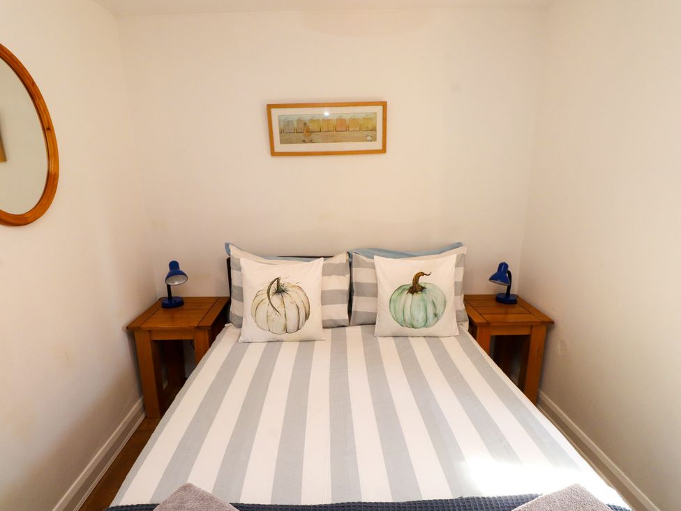 A bedroom with a bed and nightstands at Scoops’ Nook, Caernarfon