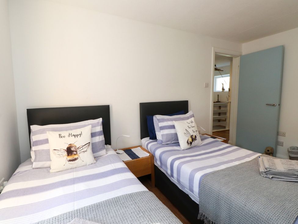 A bedroom with two beds and a shelf at Scoops’ Nook in Caernarfon