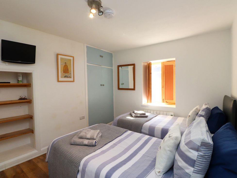 A bedroom with two beds, a television, and a wardrobe at Scoops' Nook in Caernarfon