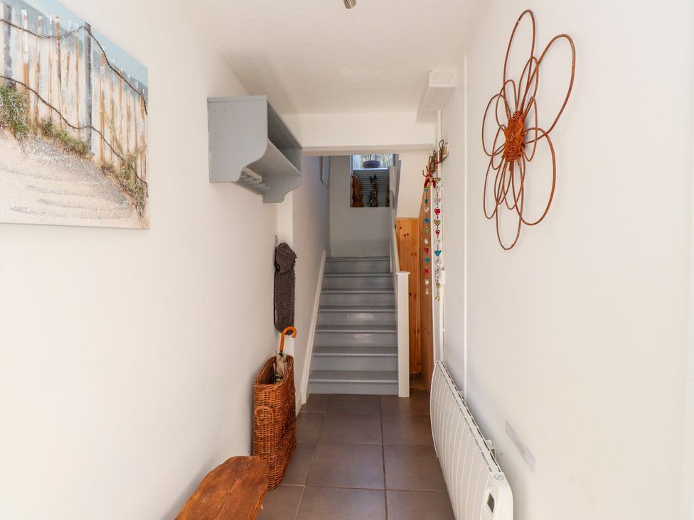 A hallway with a staircase and wall hooks at Scoops’ Nook in Caernarfon