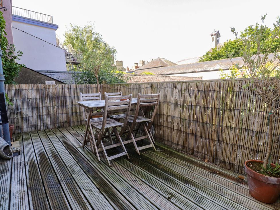 A balcony with a wooden table and chairs at Scoops’ Nook in Caernarfon