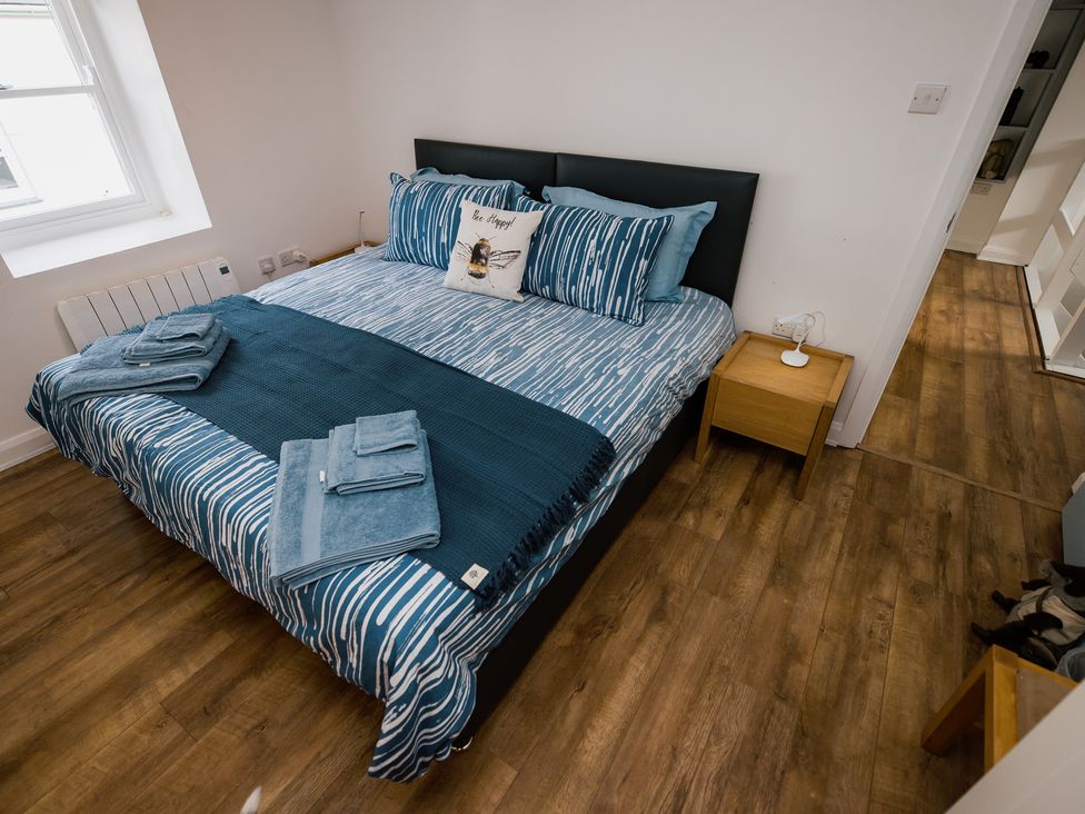 A bedroom with a bed and bedside table at Scoops’ Nook in Caernarfon