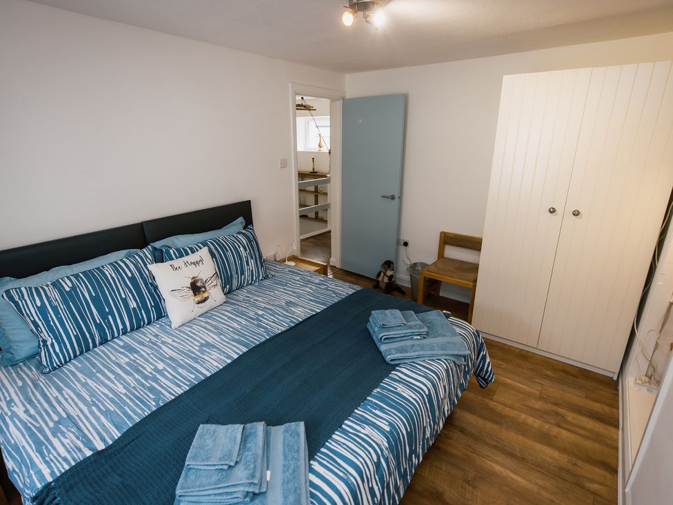 A bedroom with a bed and wardrobe at Scoops’ Nook in Caernarfon