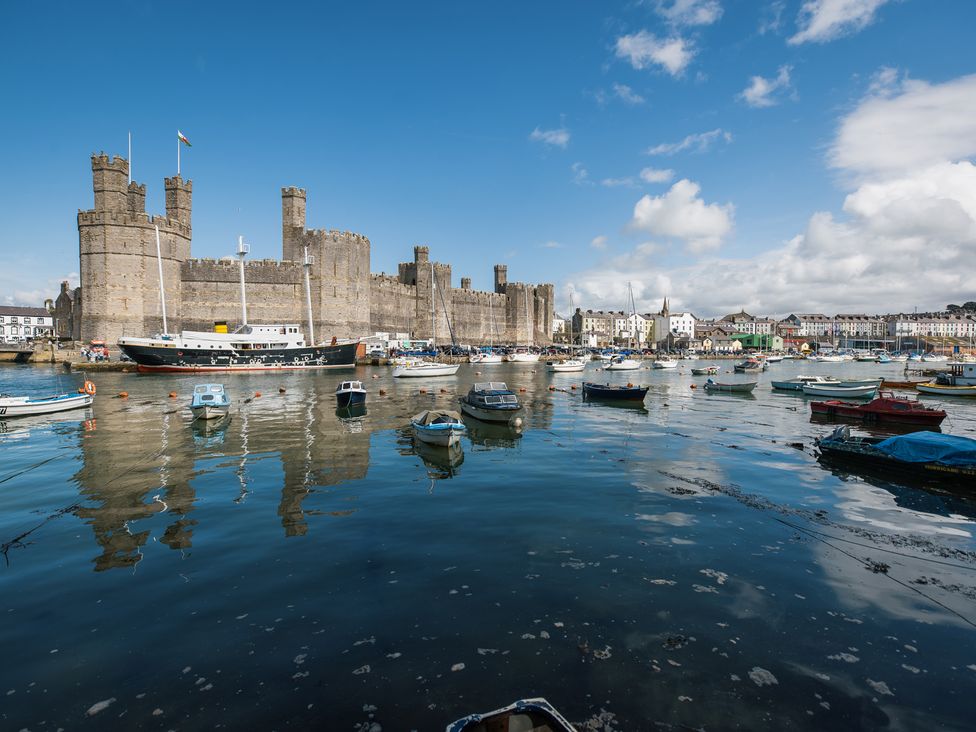 A view of a castle with boats in the water at Scoops’ Nook in Caernarfon