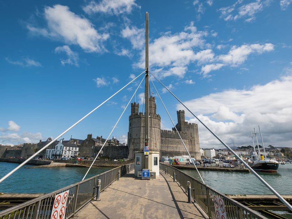 A harbor view with a castle in the background at Scoops’ Nook Caernarfon