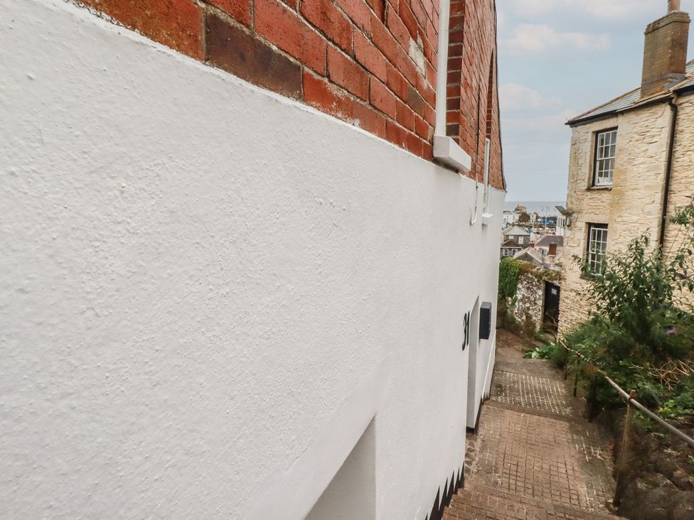 A pathway alongside a white wall and brick wall at 31 Tregoney Hill Mevagissey