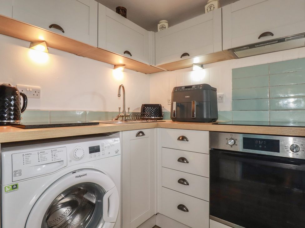 A kitchen with appliances including a washing machine and air fryer at 31 Tregoney Hill Mevagissey