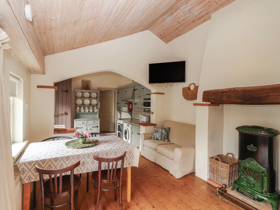A kitchen with a table and chairs at The Coach House Cottage BALLYCOMMON