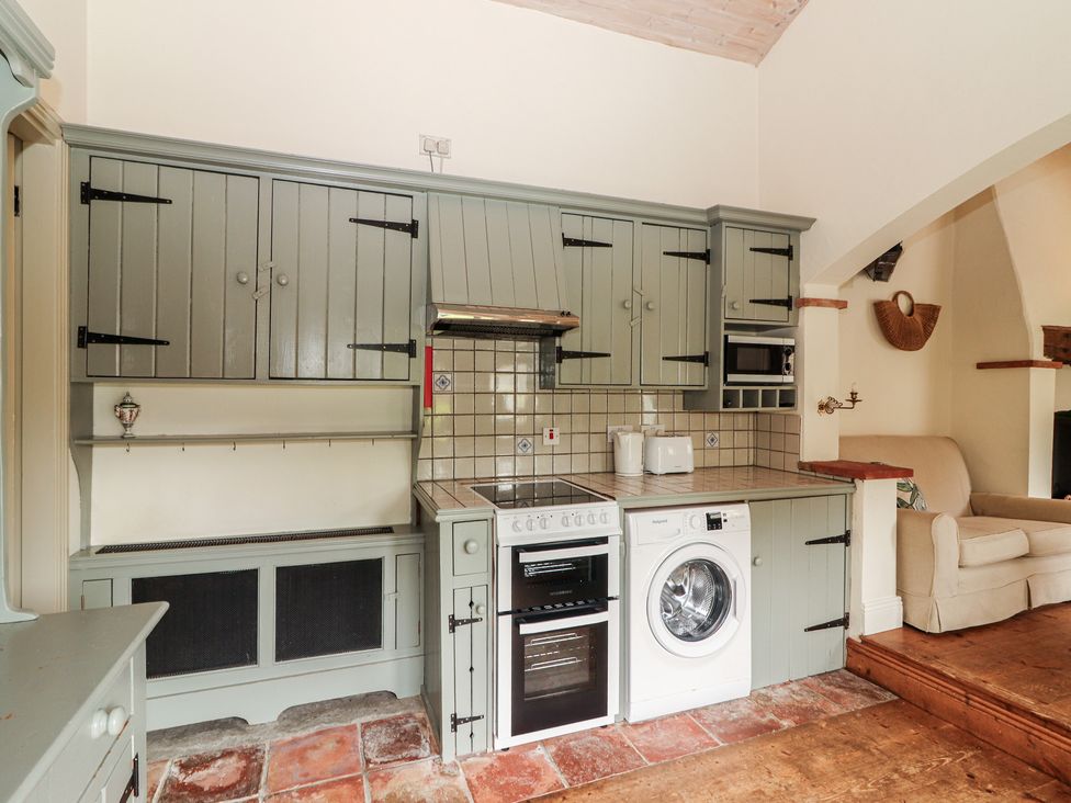 A kitchen with appliances and cabinets at The Coach House Cottage in BALLYCOMMON
