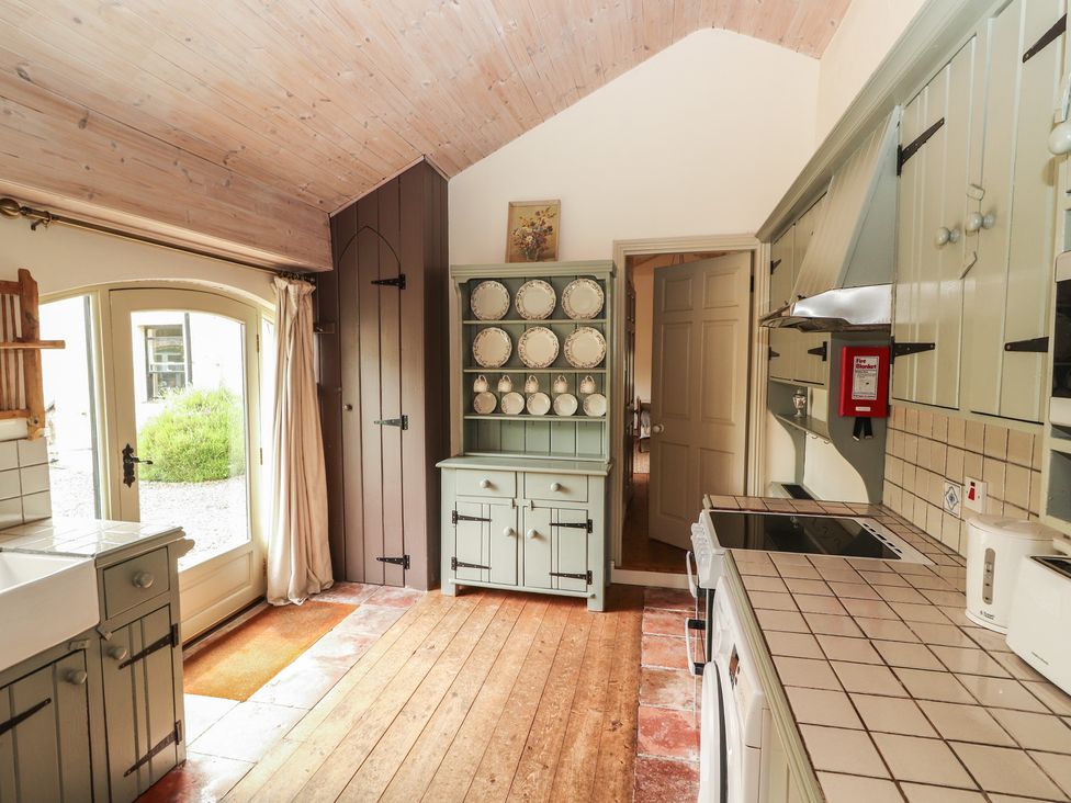 A kitchen with a sink, cupboards, and plates on display at The Coach House Cottage BALLYCOMMON
