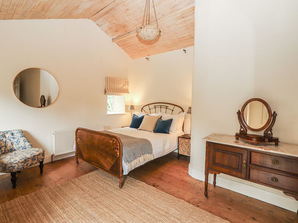 A bedroom with a bed and a chair at The Coach House Cottage BALLYCOMMON