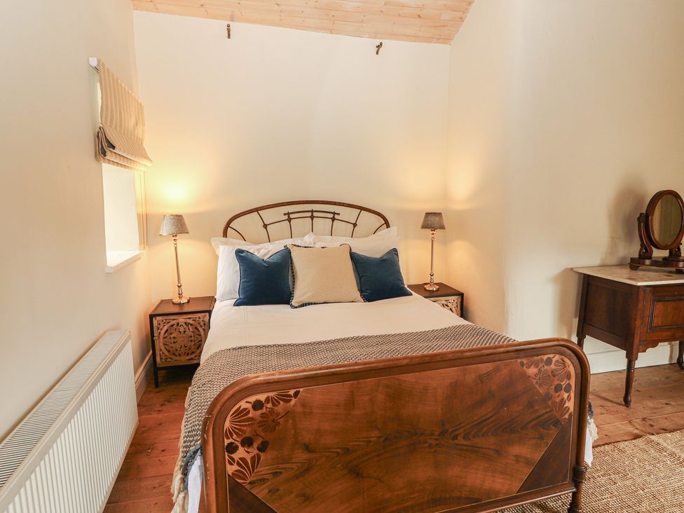 A bedroom with a bed and nightstands at The Coach House Cottage BALLYCOMMON