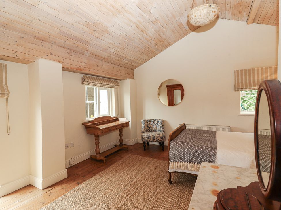 A bedroom with a bed, chair, and desk at The Coach House Cottage BALLYCOMMON