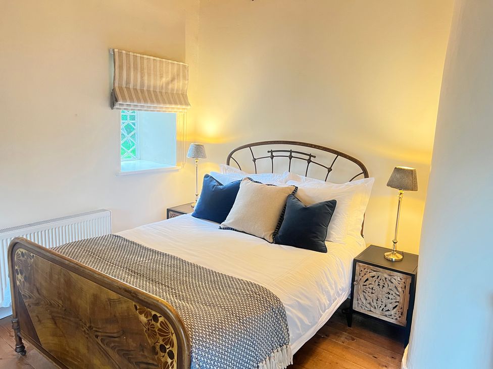 A bedroom with a bed, pillows, bedside table and lamp at The Coach House Cottage Ballycommon