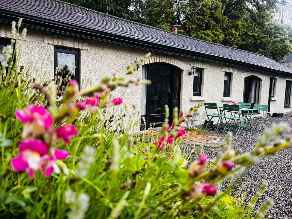 An outdoor area with a table and chairs near flowers at The Coach House Cottage in Ballycommon