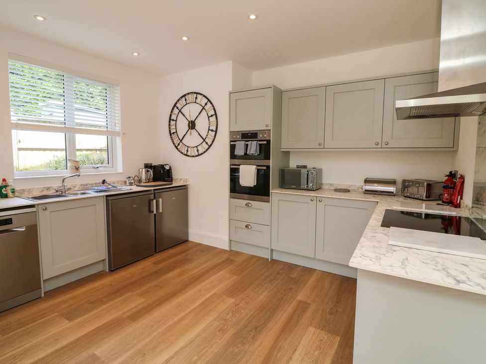 A kitchen with appliances and a clock at Wendy's Cottage in Minehead