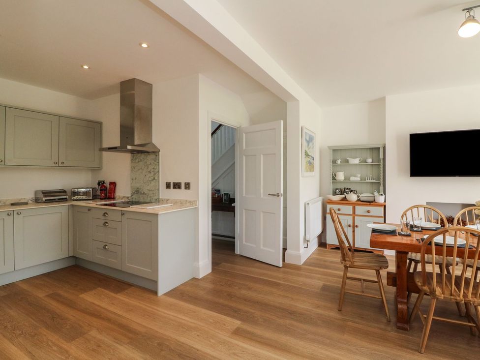 A kitchen with cabinets and dining area at Wendy's Cottage in Minehead