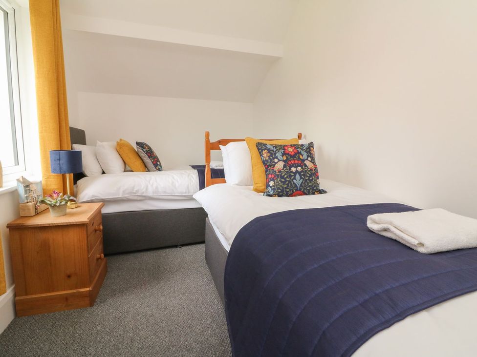 A bedroom with two beds and a side table at Wendy's Cottage in Minehead