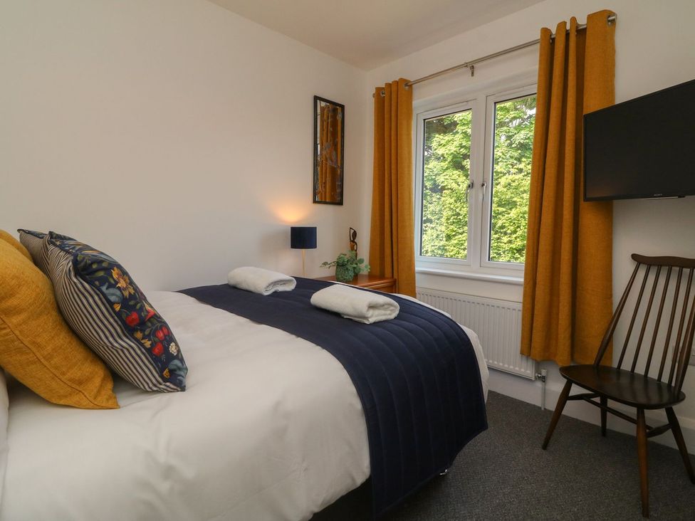 A bedroom with a bed and television at Wendy's Cottage in Minehead