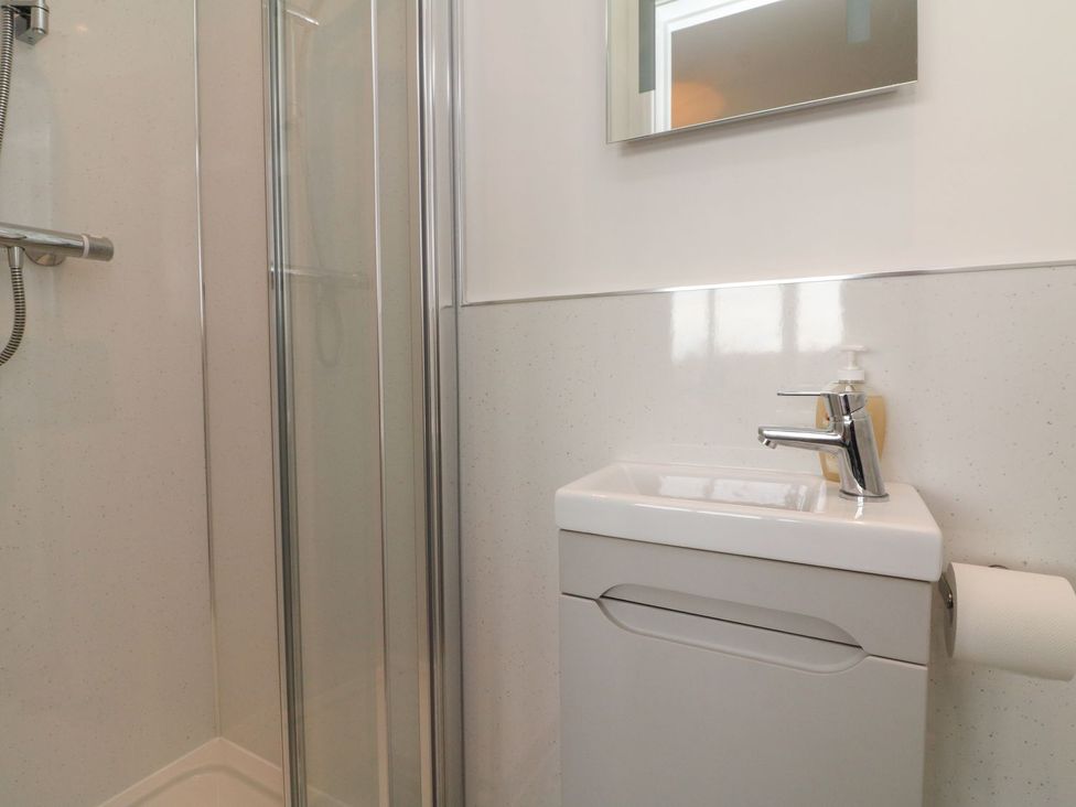 A bathroom featuring a shower, toilet, and sink at Wendy's Cottage in Minehead