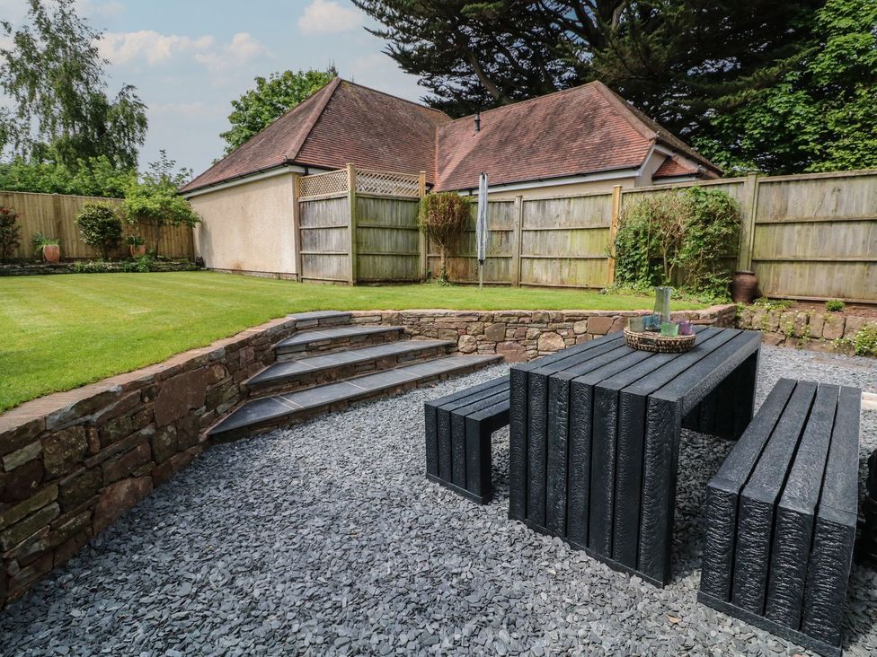 A garden with grass, table, and bench at Wendy's Cottage Minehead