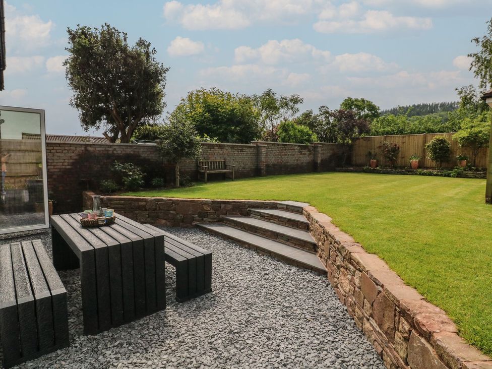 A garden with a stone table and lawn at Wendy's Cottage Minehead