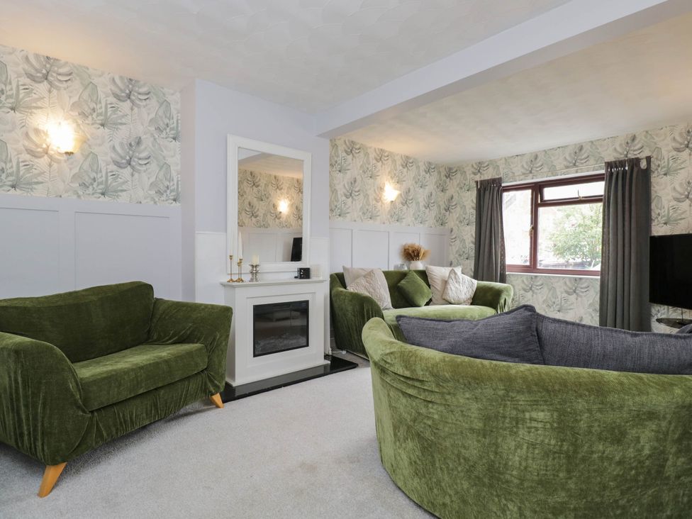 A living room with green sofas and a mirror at 1 Stanway Road