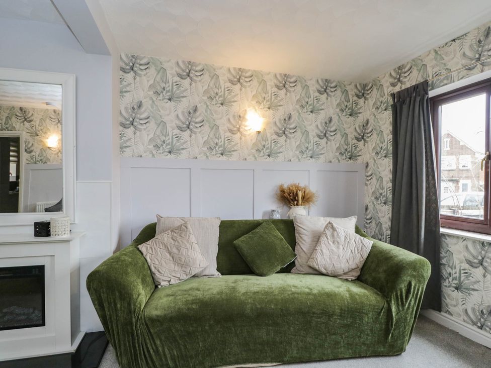 A living room with a green couch and decorative pillows at 1 Stanway Road