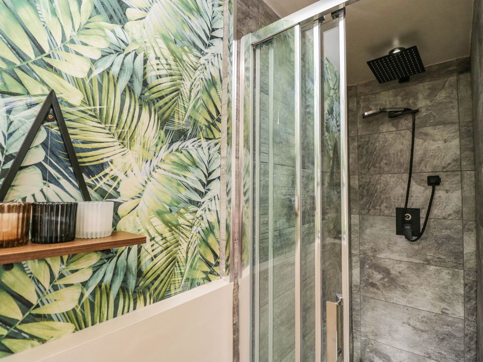 A bathroom featuring a shower with glass door and tropical wall decor at 1 Stanway Road