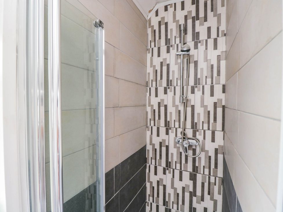 A shower with tile walls and a glass door at 1 Stanway Road