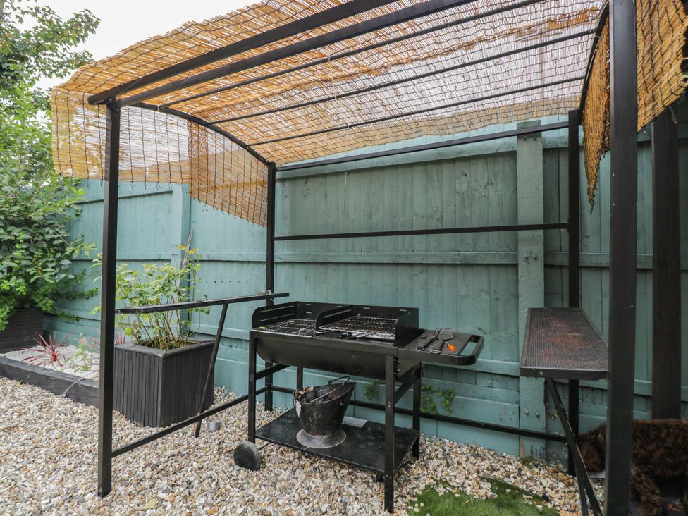 A barbecue setup with a metal grill and plant pots in the garden at 1 Stanway Road